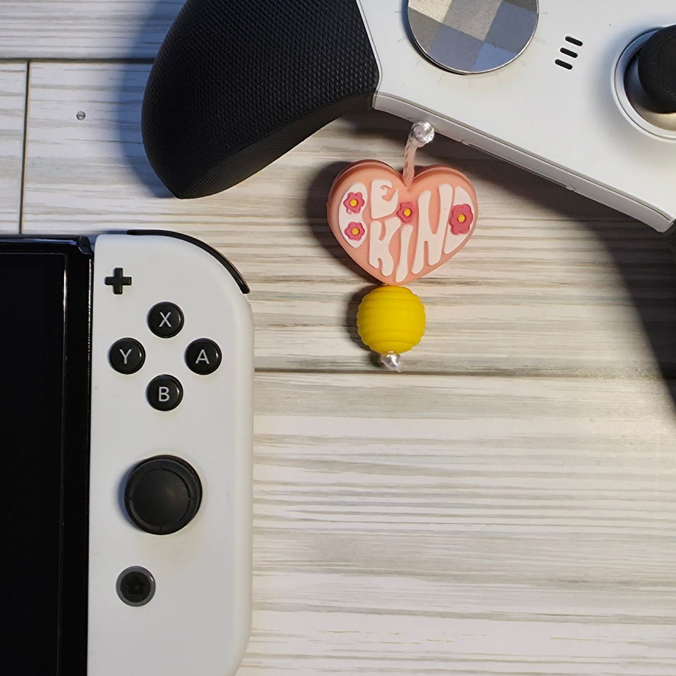 Handmade silicone Nintendo Switch charms in various colors and shapes, attached with white silky cords – designed to add charm without scratching the console.