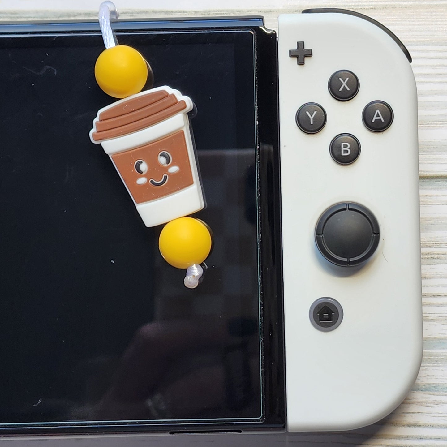 Handmade silicone Nintendo Switch charms in various colors and shapes, attached with white silky cords – designed to add charm without scratching the console.