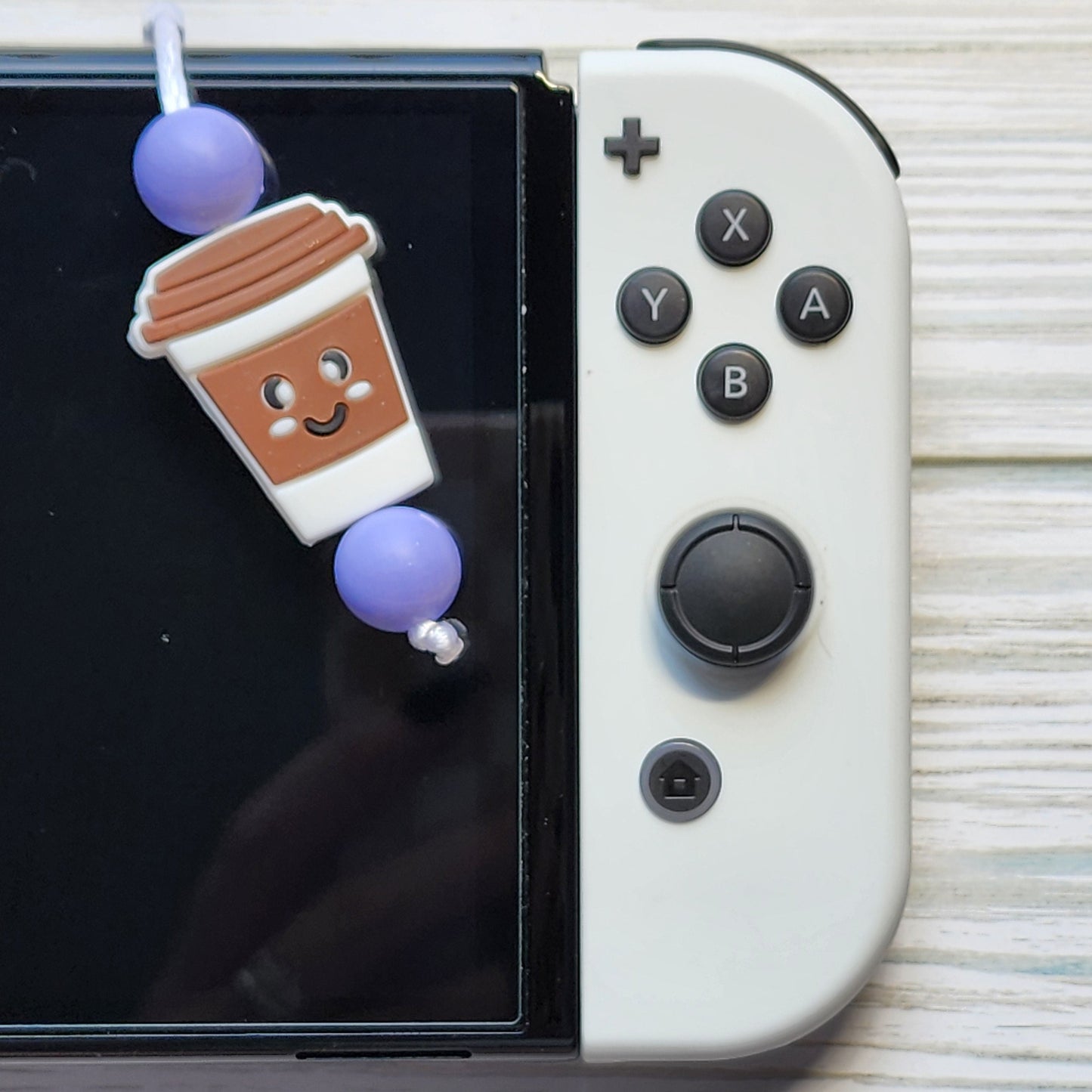 Handmade silicone Nintendo Switch charms in various colors and shapes, attached with white silky cords – designed to add charm without scratching the console.