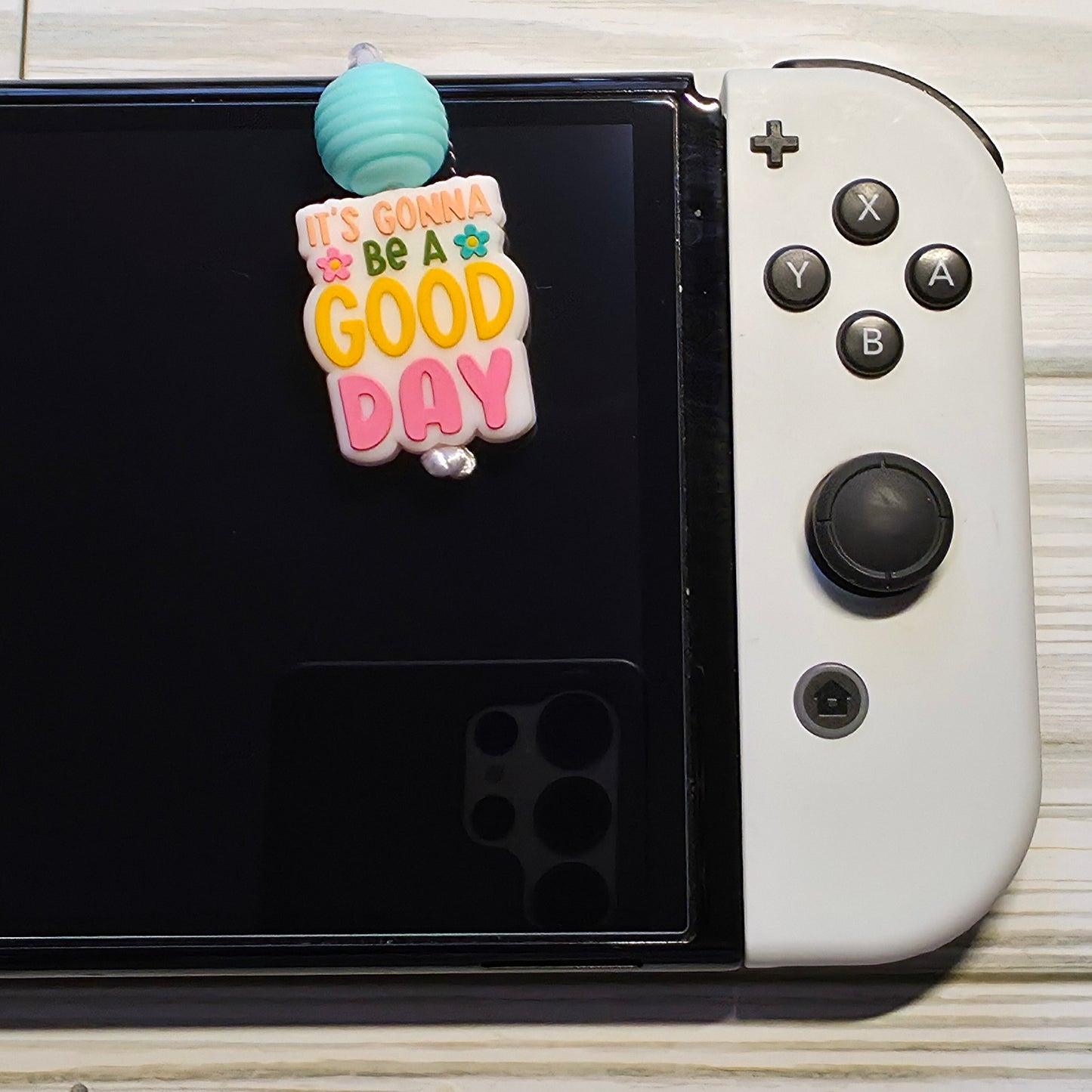 Handmade silicone Nintendo Switch charms in various colors and shapes, attached with white silky cords – designed to add charm without scratching the console.