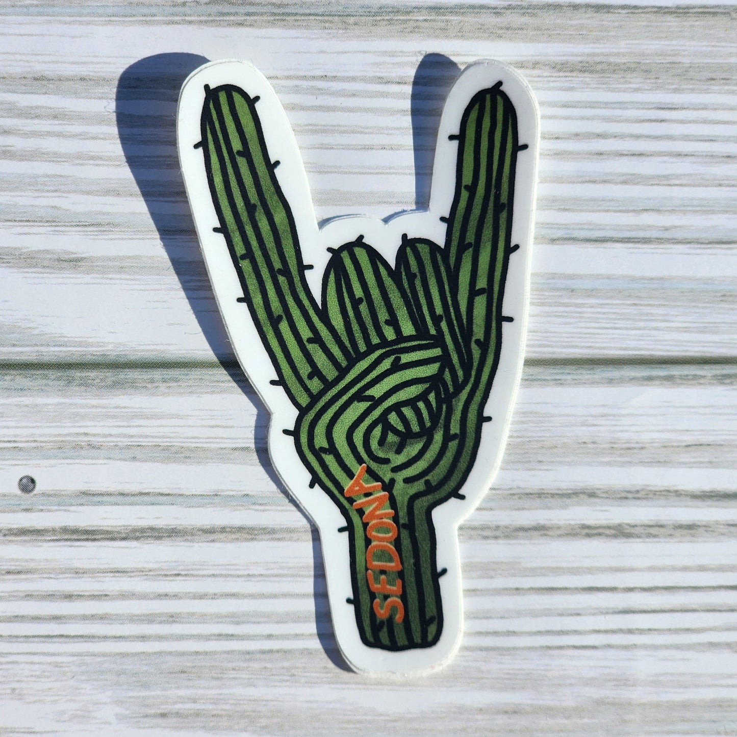 Edgy cactus sticker in the shape of a rock-on hand sign, featuring the word 'Sedona' along the base
