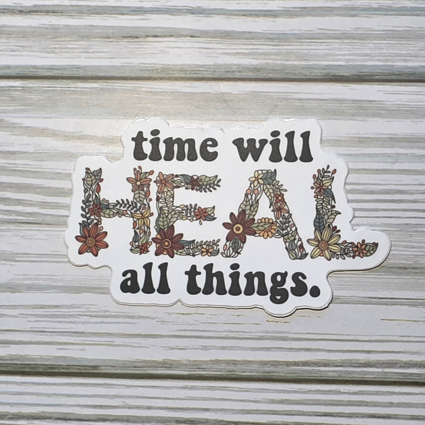 Typography design reading ‘Time Will Heal All Things,’ with the word ‘Heal’ in decorative floral lettering.