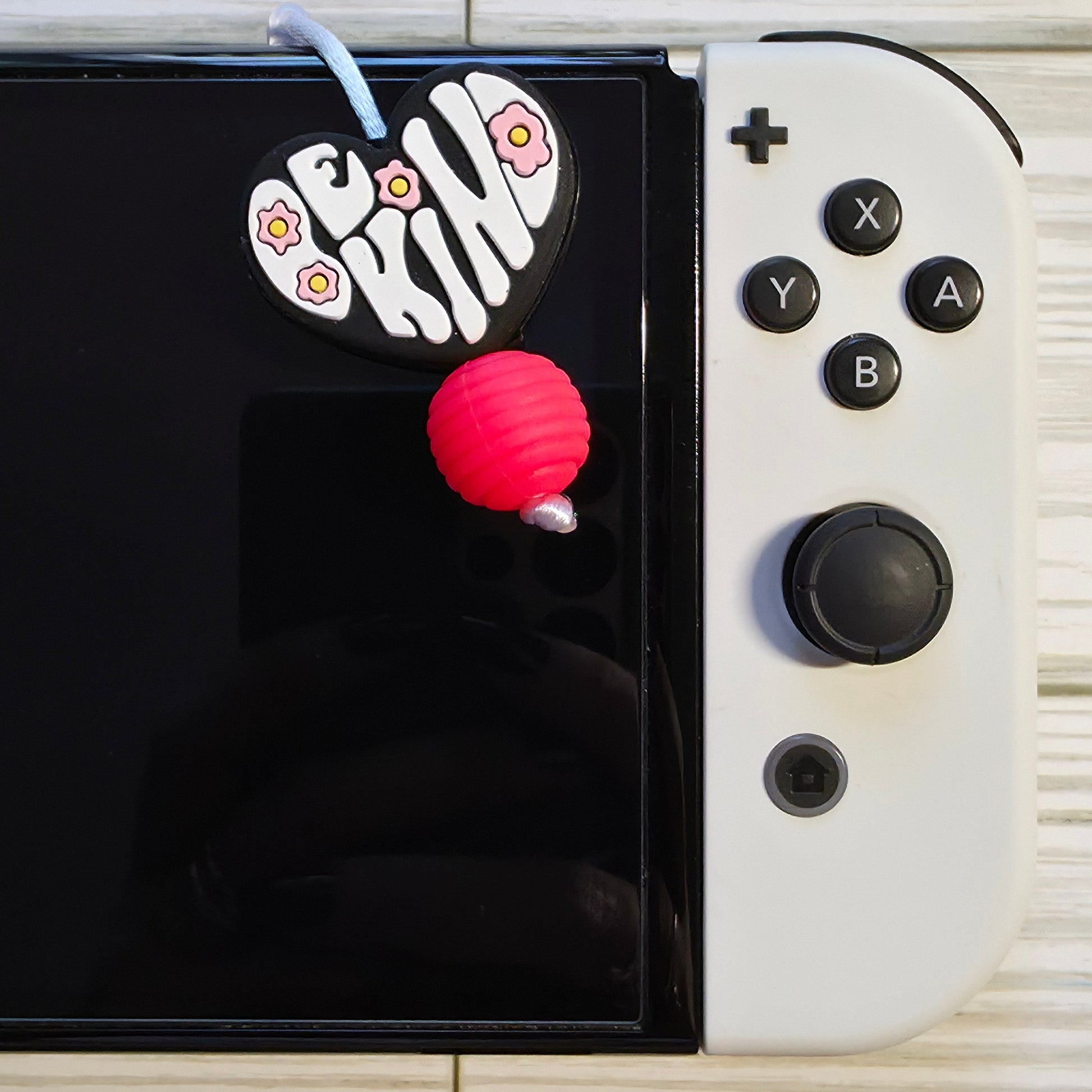 Handmade silicone Nintendo Switch charms in various colors and shapes, attached with white silky cords – designed to add charm without scratching the console.