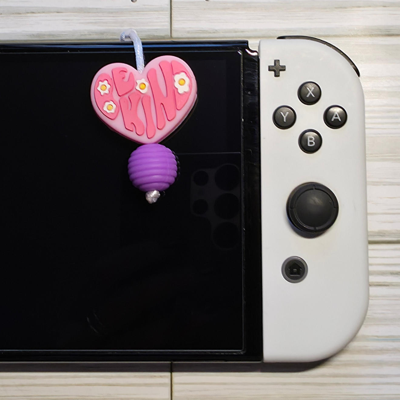Handmade silicone Nintendo Switch charms in various colors and shapes, attached with white silky cords – designed to add charm without scratching the console.