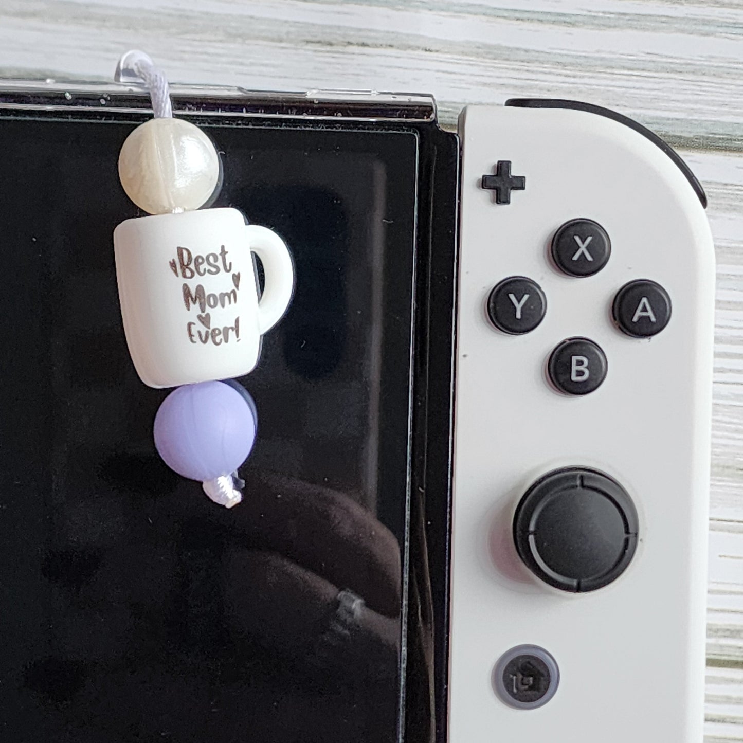 Handmade silicone Nintendo Switch charms in various colors and shapes, attached with white silky cords – designed to add charm without scratching the console.
