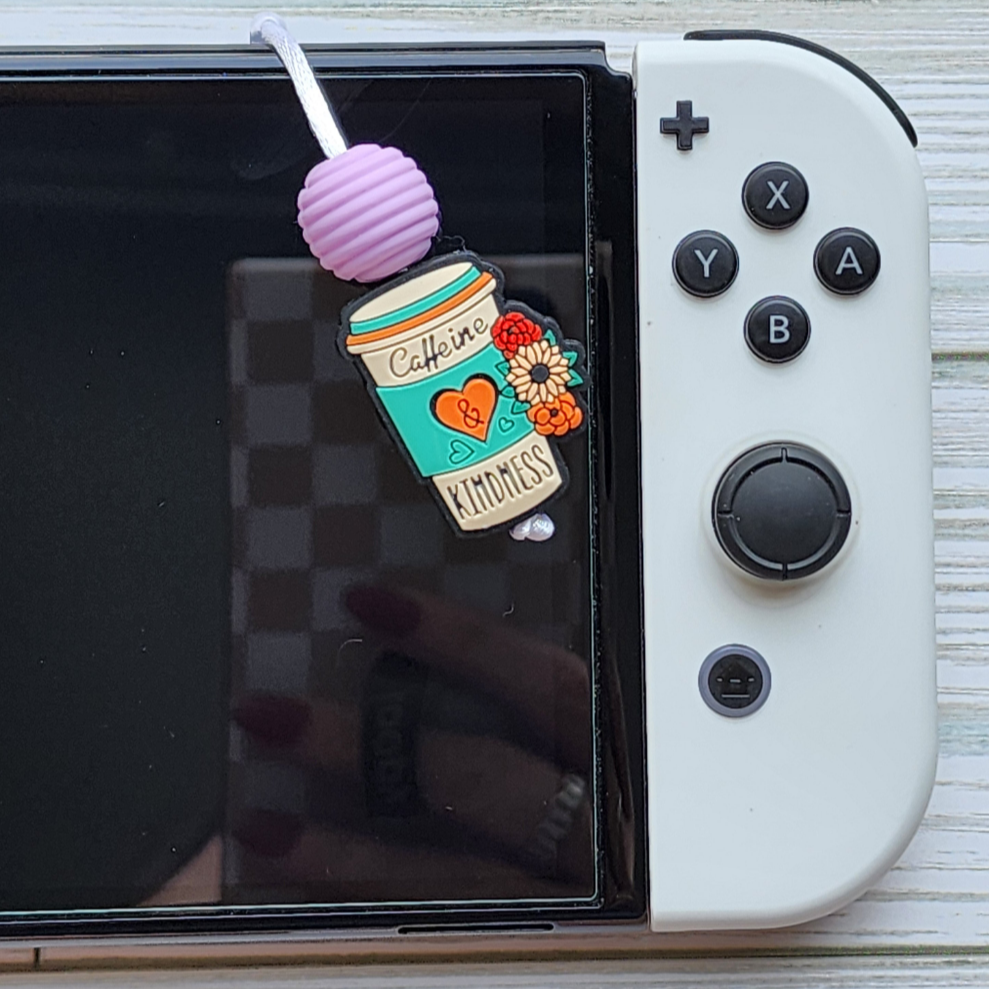 Handmade silicone Nintendo Switch charms in various colors and shapes, attached with white silky cords – designed to add charm without scratching the console.