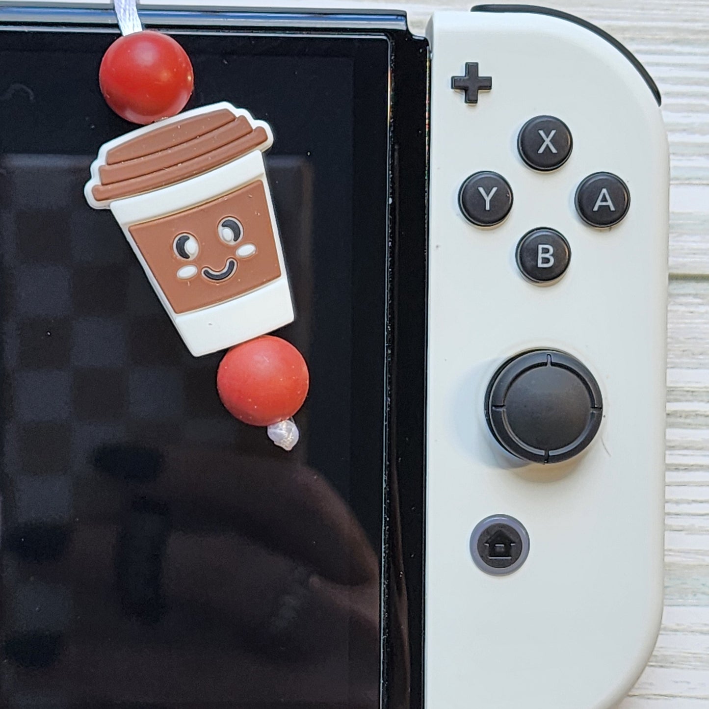 Handmade silicone Nintendo Switch charms in various colors and shapes, attached with white silky cords – designed to add charm without scratching the console.