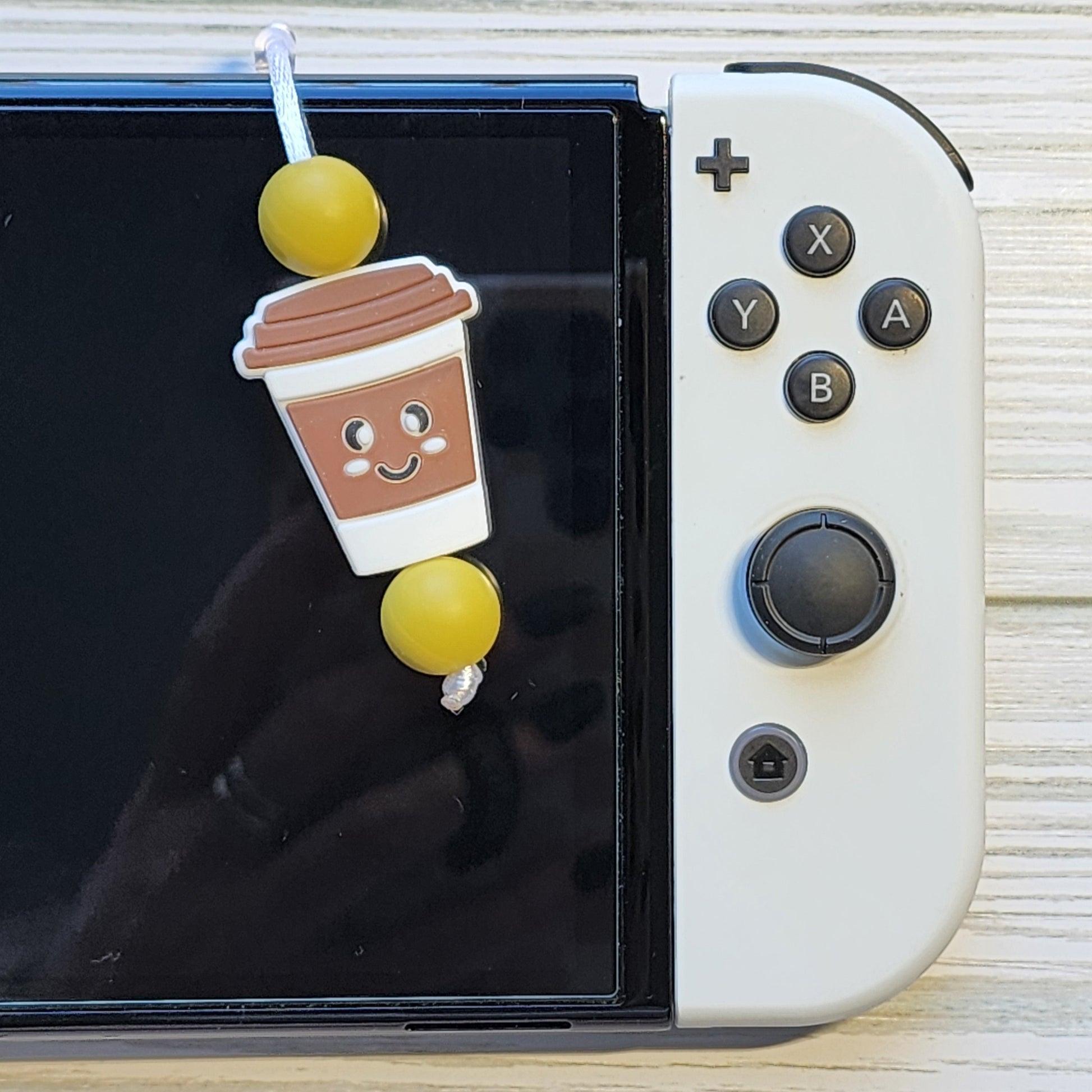 Handmade silicone Nintendo Switch charms in various colors and shapes, attached with white silky cords – designed to add charm without scratching the console.