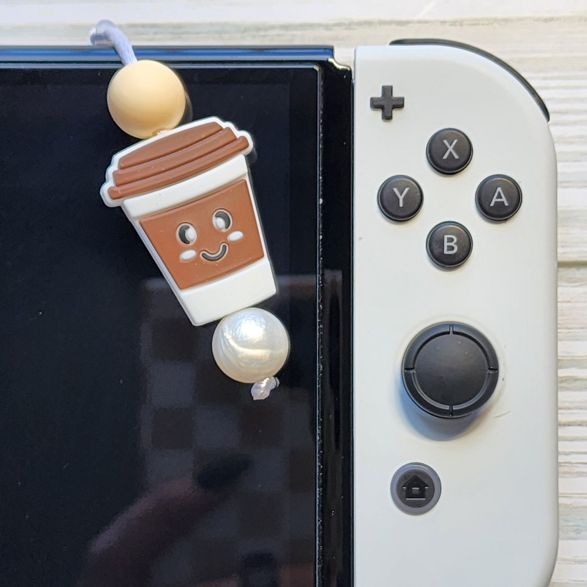Handmade silicone Nintendo Switch charms in various colors and shapes, attached with white silky cords – designed to add charm without scratching the console.