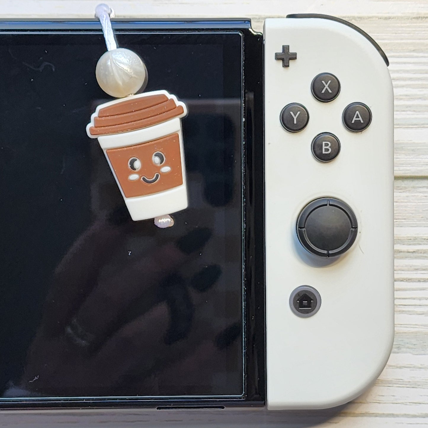 Handmade silicone Nintendo Switch charms in various colors and shapes, attached with white silky cords – designed to add charm without scratching the console.