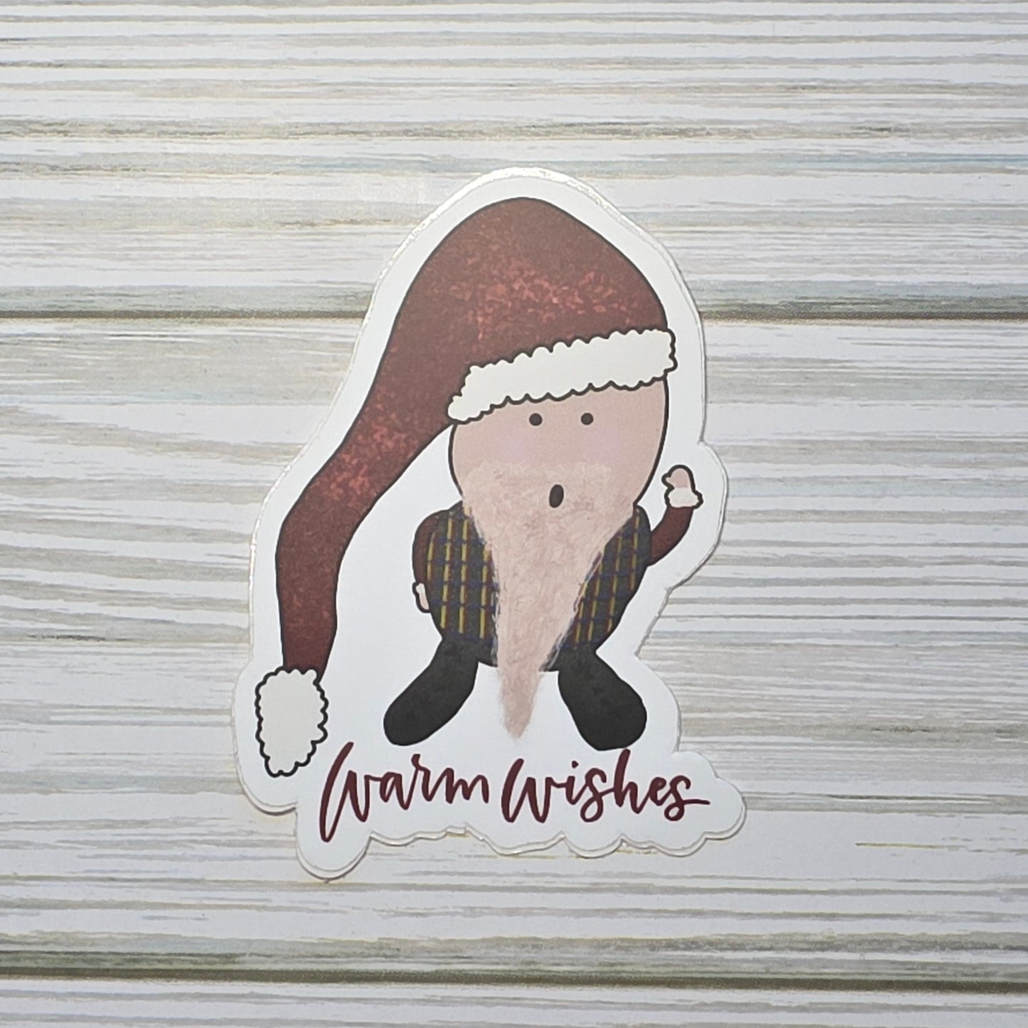 Cute gnome with a scruffy beard wearing a winter hat, standing above the words ‘Warm Wishes.'