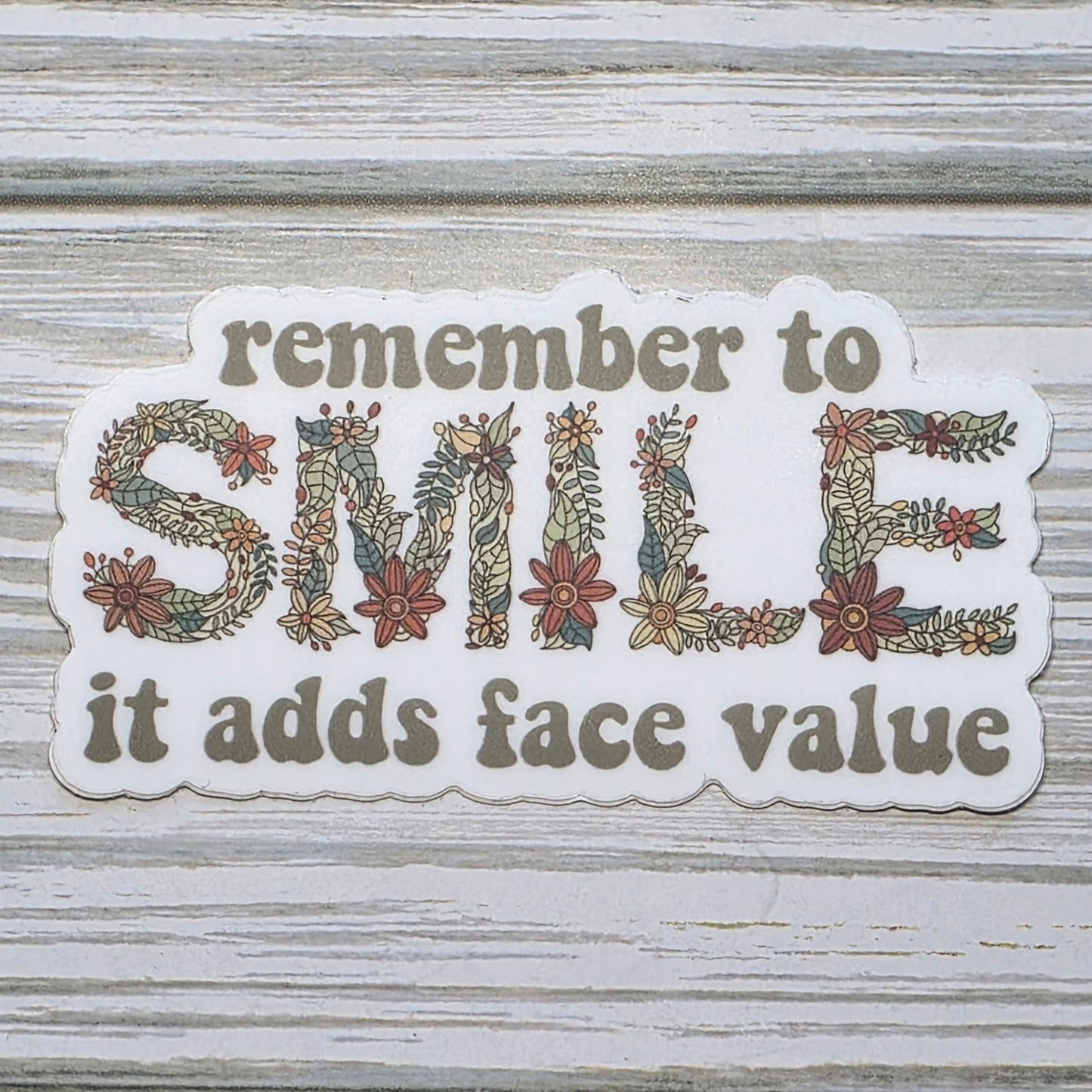 Typography design reading ‘Remember to Smile It Adds Face Value,’ with the word ‘Smile’ in decorative floral lettering.