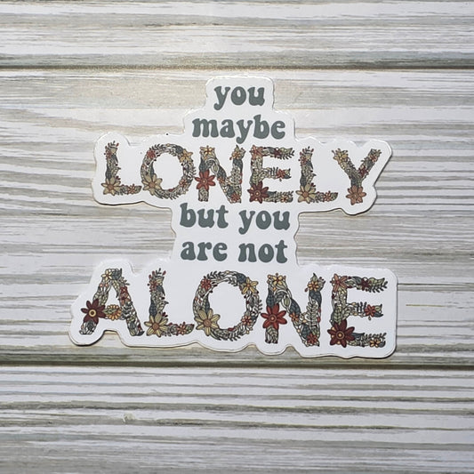 Typography design reading ‘You Maybe Lonely But You Are Not Alone,’ with the word ‘Lonely and Alone’ in decorative floral lettering.